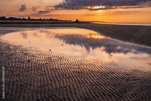Fototapeta Naklejka Na Ścianę i Meble -  summer sunrise where the lagoon meets the sea with reflection of the clouds inside the puddles created by the tide, Bibione Pineda, Venice