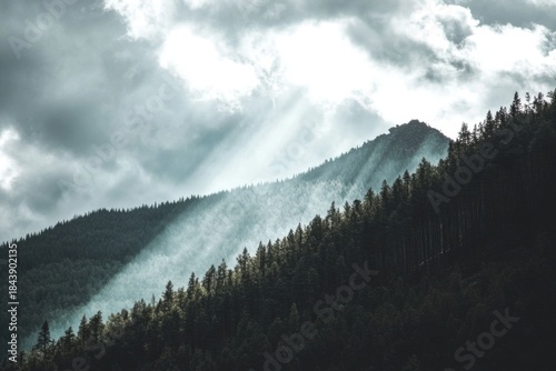 Serene mountain landscape with sunlight rays breaking through clouds