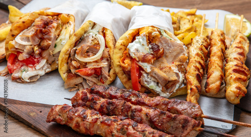 Fototapeta Naklejka Na Ścianę i Meble -  Gyro sliced meat pita bread wraps, pork souvlaki skewers, traditional street food, closeup