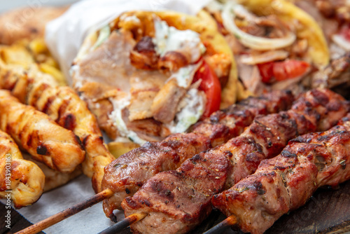 Fototapeta Naklejka Na Ścianę i Meble -  Gyro sliced meat pita bread wraps, meat souvlaki skewers, traditional street food, closeup