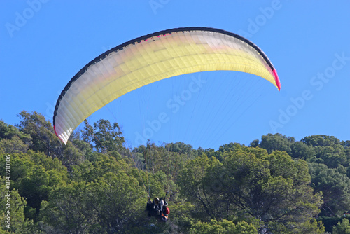 Tandem Paraglider flying in a blue sky	