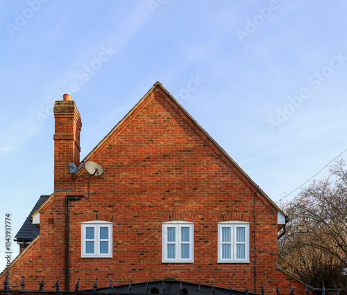 Εκτύπωση καμβά Red brick dwelling showing chimney, windows, and roofline against a clear sky, r