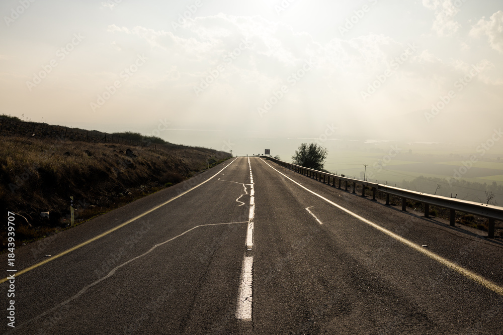 Fototapeta premium Empty rural road leading to a misty horizon.