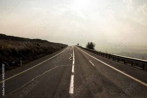 Empty rural road leading to a misty horizon.