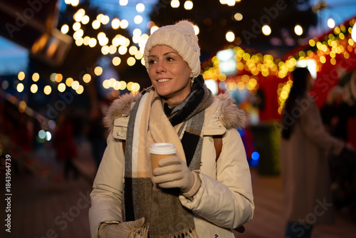 Woman enjoying warm coffee at festive winter market