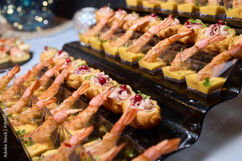 Obraz premium Elegant dining presentation, Sophisticated arrangement of canapes on stylish table setting, Exquisite black trays with gourmet delicacies showcased in upscale event ambiance