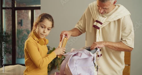 Father guides daughter through homework with nurturing gestures