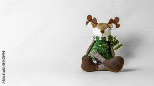 Funny plush toy reindeer in a winter woolen suit on gray background