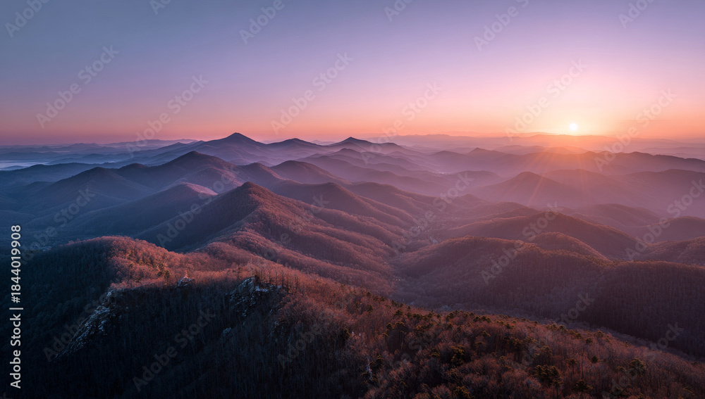 Naklejka premium Sunrise over mountain peaks with soft mist and viintimate apparelnt sky, capturing the serene beauty of dawn in a rugged landscape