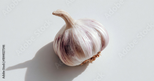 A fresh garlic clove with white papery skin and natural texture