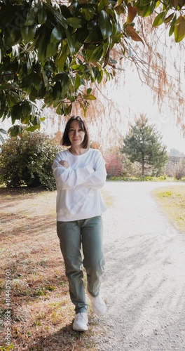 Woman in stylish clothes walking outdoor in sunny spring park