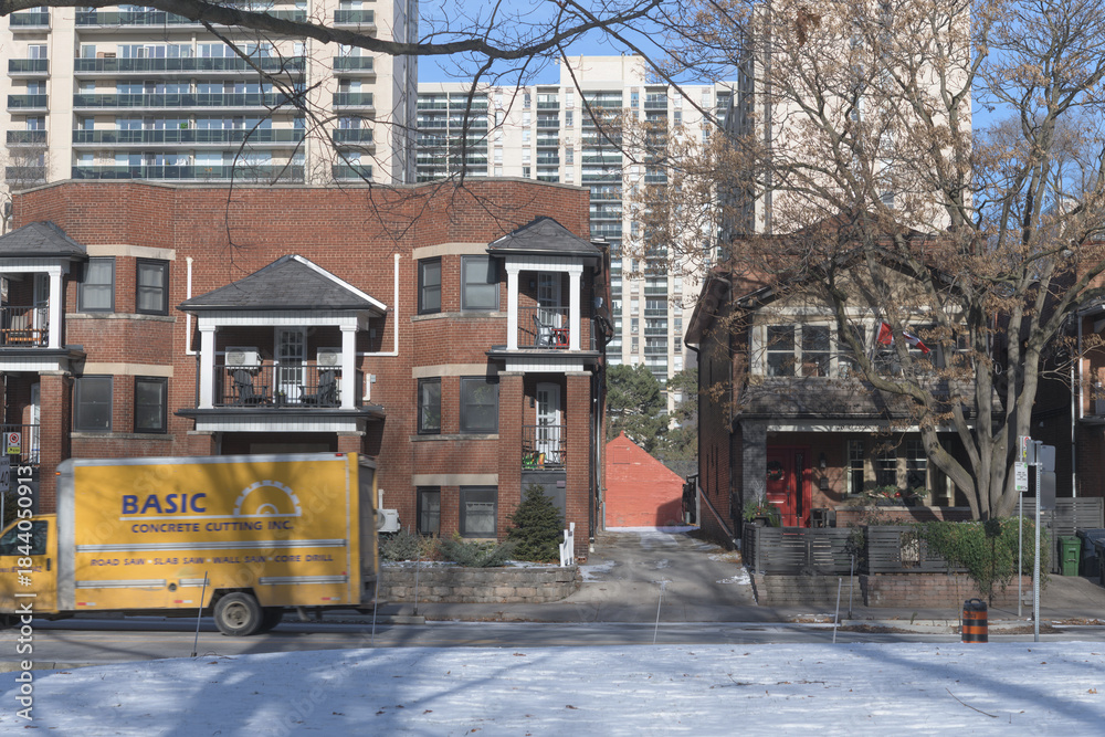 Fototapeta premium historic apartment blocks across from High Park and a Basic Concrete Cutting service vehicle on Bloor St W east of High Park Blvd, Toronto