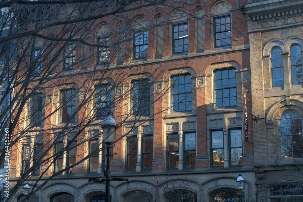 Fototapeta premium exterior of Dixon/Beardmore Block (section with brick at 45-49 Front St E) projecting sign of Winners Dept Store, sunset, Toronto
