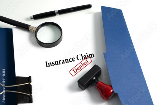 Insurance Claim Form with Denied Stamp and Magnifying Glass on Blue Folder
