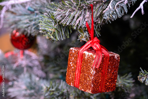 Close-up of a beautifully decorated ornament hanging on a artificial Christmas tree.