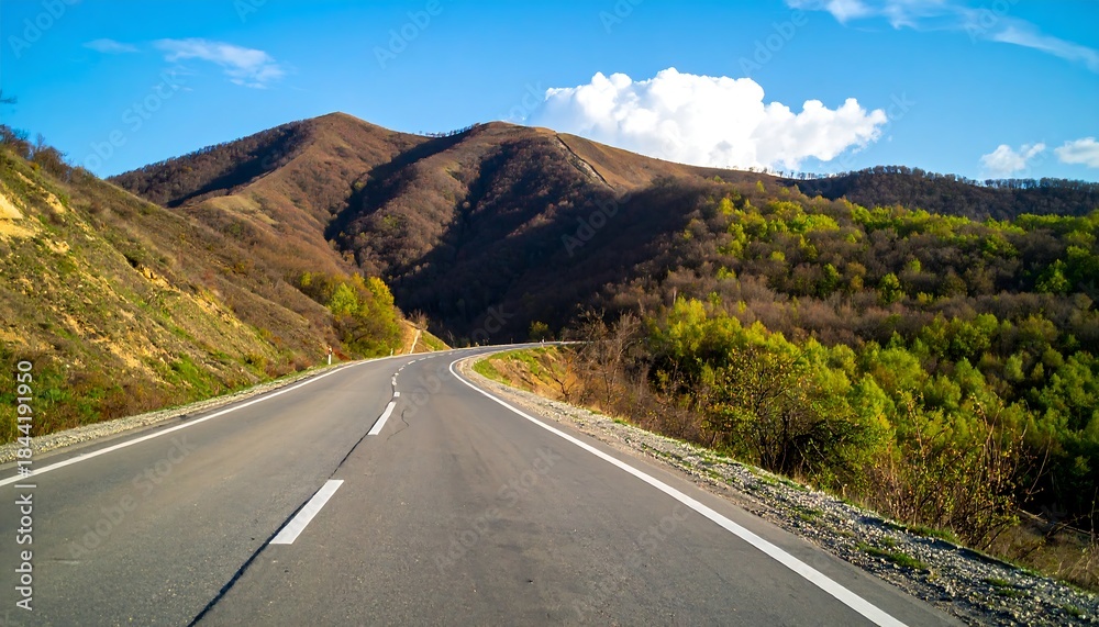 Naklejka premium Winding road through mountains on a sunny day