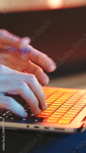 close up Man typing on a modern laptop, streetlights at night. The background is blurred, cinematic effect