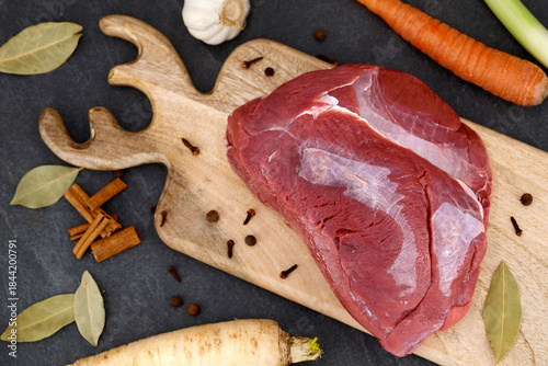 Картината върху платно top view of raw venison haunch on wooden board with spices and vegetables, ingre