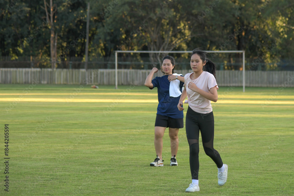 Obraz premium Two people exercising outdoors, jogging together on a green grass field during a sunny afternoon.