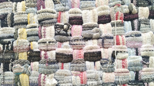 A close-up view of a textured textile art piece with a repeating pattern of woven cylindrical shapes.