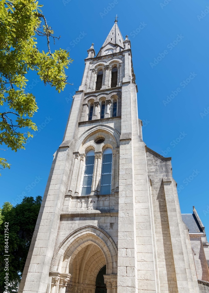Obraz premium Romanesque church of Saint-Gaudens of Fouras in Charente-Maritime. Façade with a arch porch and romanesque-inspired bell tower surmounted by a spire framed by four pinnacles