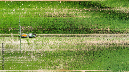 Aerial drone view of tractor fertilizing green cultivated agricultural field, modern agriculture in the Netherlands
