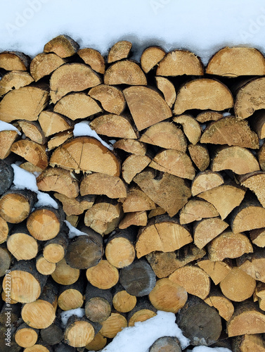 A pile of firewood lies in a pile, chopped for burning in the stove. Preparation for winter. A pile of logs for firewood. Background with firewood. Buying and selling firewood for the winter.
