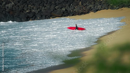 Big wave surfing in Hawaii on Waimea Bay. Person enters the sea with surfing board on the Hawaiian shore in Waimea Bay. Surfing the waves in Hawaii. Oahu island
