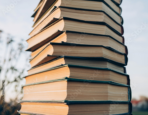 A colorful stack of old books and paper documents represents knowledge and the literature of education and learning
