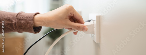 Close-up hands pull off electronic device plug after finish used.