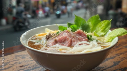 Authentic Vietnamese beef pho noodle soup, delicious and warm food dish served in busy street setting on wood table