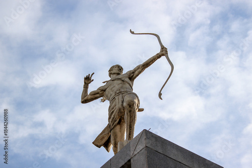 Foto Bronze archer statue standing tall against a cloudy blue sky background around the Gelora Bung Karno Sports Complex