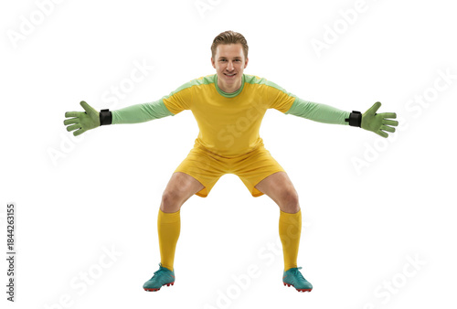 Focused male soccer goalkeeper in yellow uniform and green gloves ready to block a shot on white background.