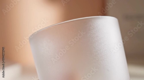 Close-up of a hand holding a frosted glass cup, showcasing its elegant design and texture.