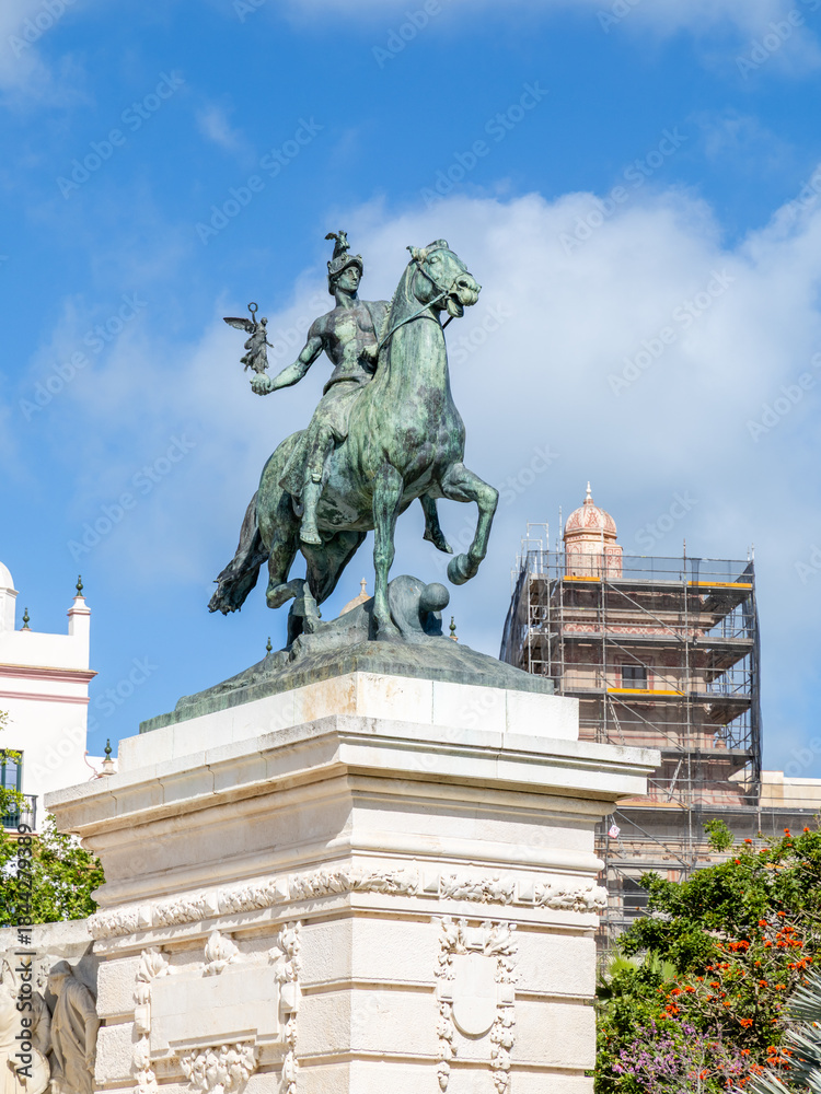 Obraz premium Cadiz, Spain - April 16, 2025: monument in homage to the Constitution of 1812 in Cadiz, with tourists swimming in the sea during the Easter holidays in Cadiz, Spain.