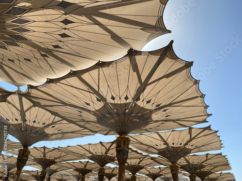 Schilderij op canvas Low-angle view of the majestic retractable umbrellas providing shade in the courtyard of Al Masjid an Nabawi in Medina