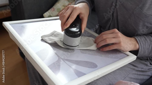 woman takes care of clothes at home, cuts off lint with tool