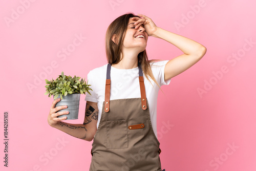 Tableau sur toile Gardener woman holding a plant isolated on pink background smiling a lot