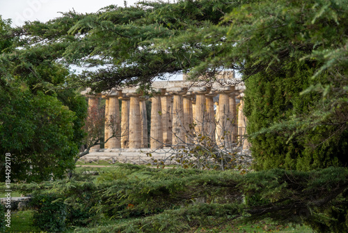 Side view of ancient Temple of Hera framed by lush green trees