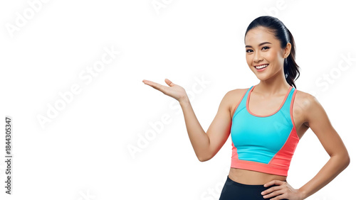 Smiling fit Asian woman in vibrant activewear presenting with open hand, embodying a healthy lifestyle and promoting wellness or fitness products against a crisp white background