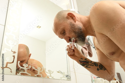 Man brushing teeth in bathroom while preparing for the day and focusing on personal care routine