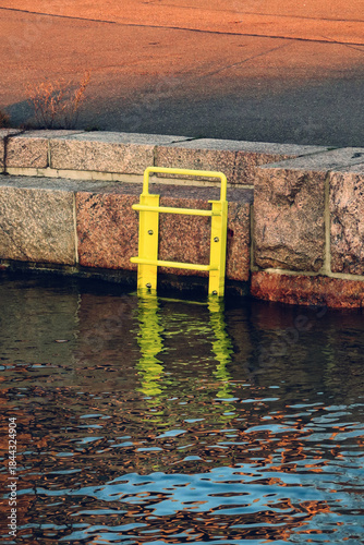 Yellow ladder leading into water at the seafront.