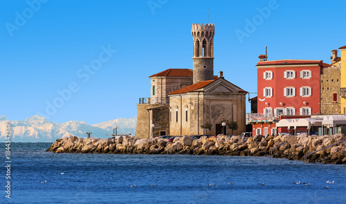A view of Our Lady of Health Church in the old Slovenian town of Piran. Cityscape of Piran with snowy mountains in the background