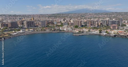 Aerial view of San Giovanni li Cuti beach. It is a small seaside village in the eastern part of the city of Catania, Sicily, Italy. In the background, on the horizon, is Mount Etna in silhouette.
