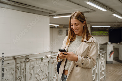 Bilde på lerret Woman walking and smiling while typing on her phone