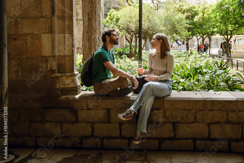 Fotografie Woman gesturing and talking to man who listens while they sit on a wall