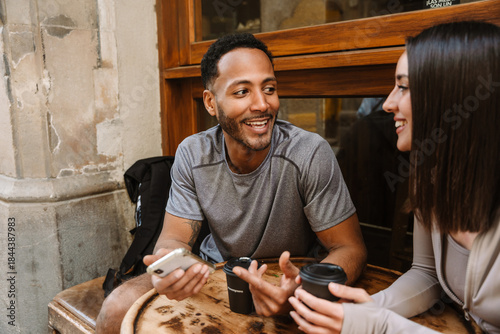 Canvas Print Male athlete holding phone and talking to female athlete holding cup while they