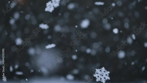 Close-up of falling snowflakes in slow motion, winter wonderland scene.