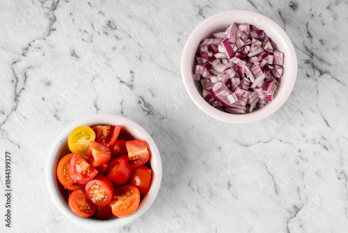 Tablou pe pânză chopped cherry tomatoes and diced red onion prepared for cooking on a marble bac