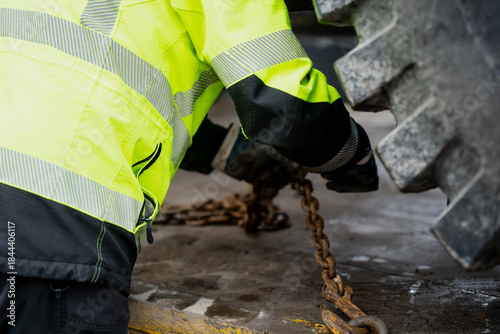 Φωτογραφία Close up of safety worker fastening metal chain on heavy equipment tire while we